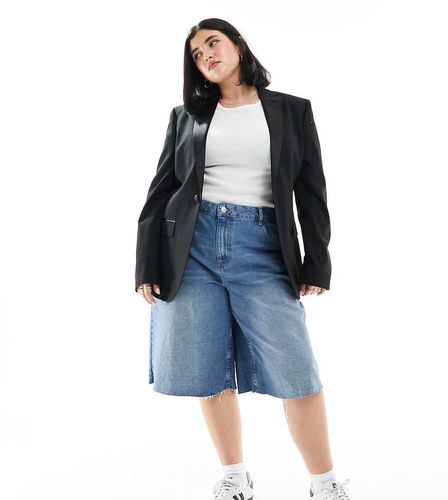 ASOS DESIGN Curve - Pantaloncini in denim larghi taglio lungo lavaggio medio - ASOS Curve - Modalova