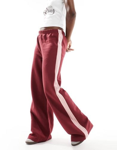 Pantaloni oversize sportivi bordeaux con riga laterale rosa - ASOS DESIGN - Modalova